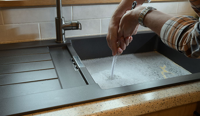 A person cleaning clogged kitchen sink