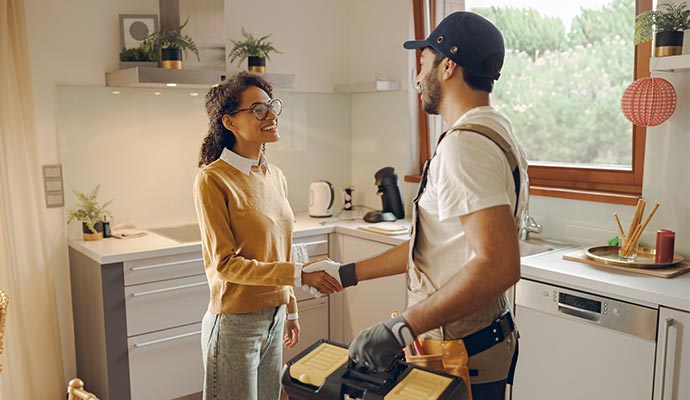 Technician shaking hands with homeowner in a modern kitchen, representing trusted plumbing service