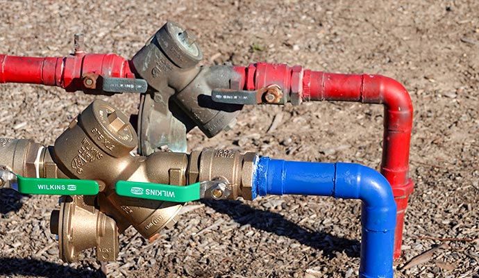 Brass Wilkins Zurn backflow preventer connected to red and blue pipes