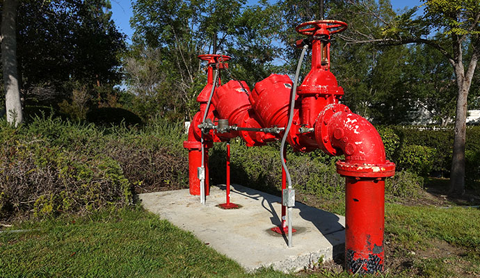 Large red commercial double check backflow preventer system on concrete pad