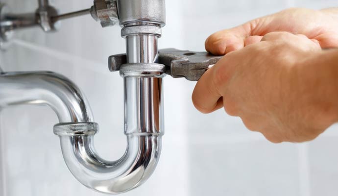 Plumber adjusting drainage pipes beneath a sink
