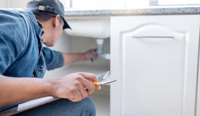 Plumber inspecting sink pipes during a plumbing service