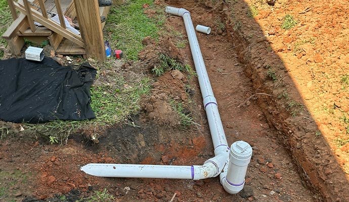White PVC sewer pipe installed in an open yard trench